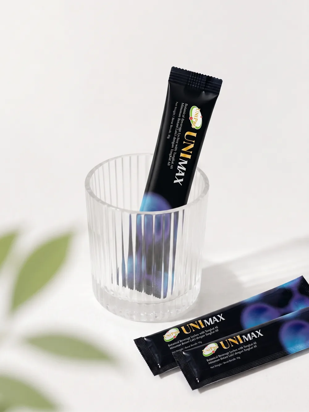 UNI MAX 10g sachet in a ribbed glass, ready to drink, with a botanical leaf